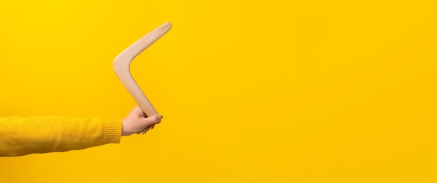 Boomerang en mano femenina sobre amarillo