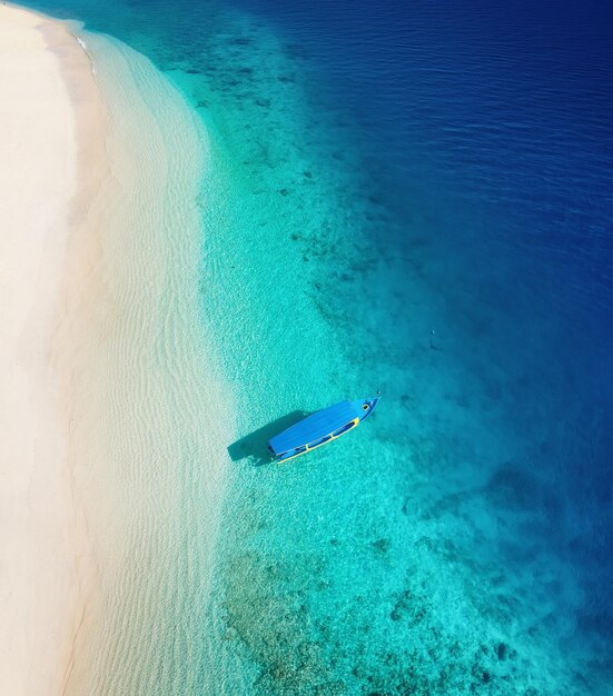 Boot auf der Wasseroberfläche von oben Türkisfarbenes Wasser Hintergrund von oben Sommermeerblick aus der Luft Insel Gili Meno Indonesien Reisebild