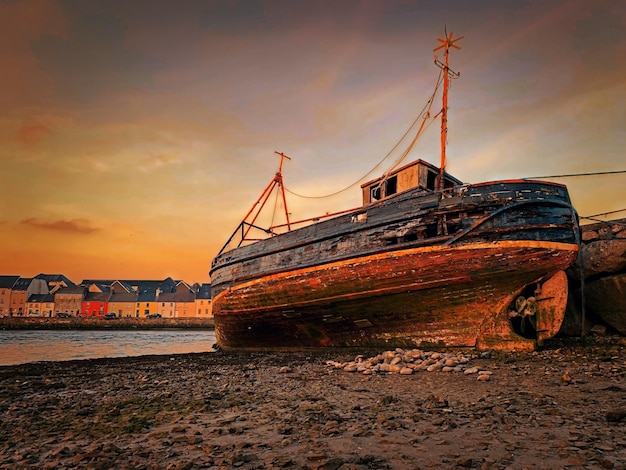 Foto boot, das bei sonnenuntergang am strand gegen den himmel verankert ist