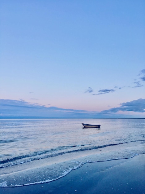 Boot, das bei Sonnenuntergang auf dem Meer gegen den Himmel verankert ist