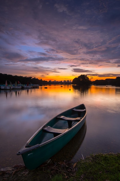 Boot, das bei Sonnenuntergang auf dem See gegen den Himmel verankert ist