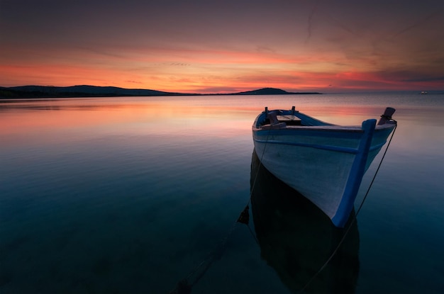 Boot, das bei Sonnenuntergang auf dem See gegen den Himmel verankert ist