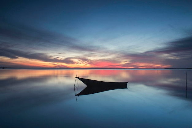 Boot, das bei Sonnenuntergang im Meer gegen den Himmel verankert ist