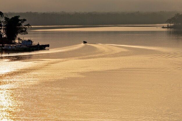 Boot, das Wellen im goldenen Wasser des Flusses bei Sonnenaufgang erzeugt. Itanhaem, Bundesstaat Sao Paulo, Brasilien