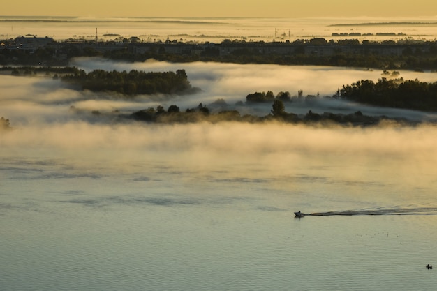 BOOT SCHWIMMT AUF DEM FLUSS DURCH NEBEL