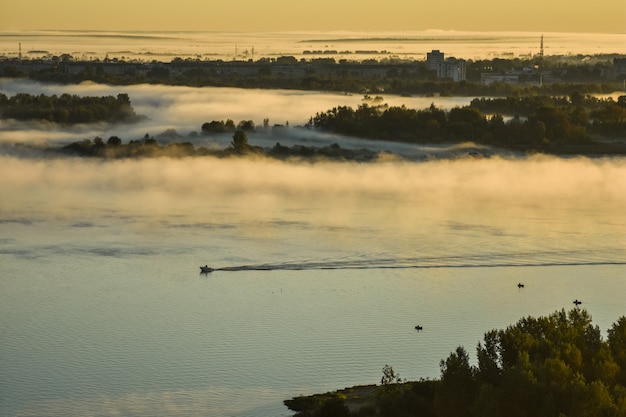 BOOT SCHWIMMT AUF DEM FLUSS DURCH NEBEL