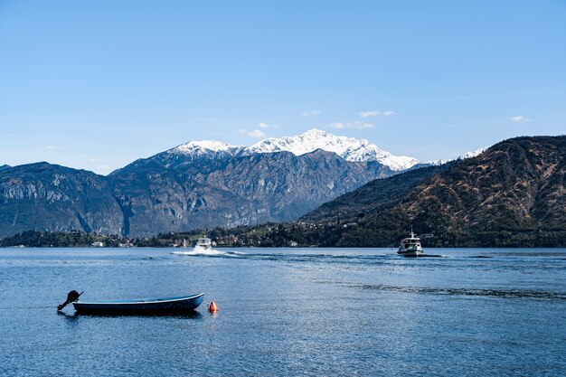 Boot steht am Comer See vor der Kulisse von Bergen und Segelyachten italien