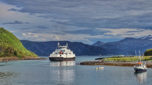 Boot und Schiff segeln im Fluss durch Berge gegen den Himmel