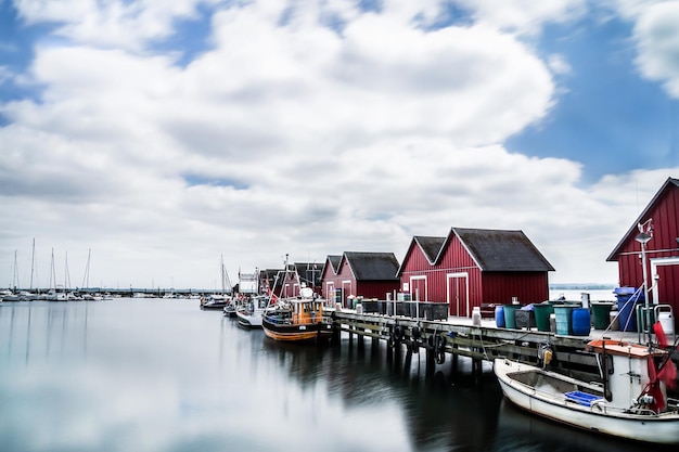 Foto boote, die am pier am hafen am see gegen einen bewölkten himmel verankert sind