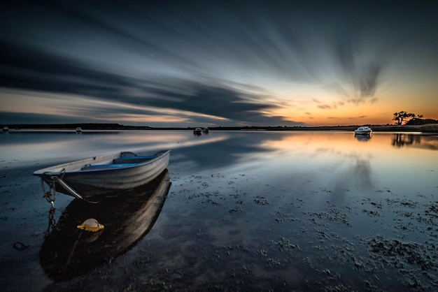 Boote, die bei Sonnenuntergang am Strand gegen den Himmel verankert sind