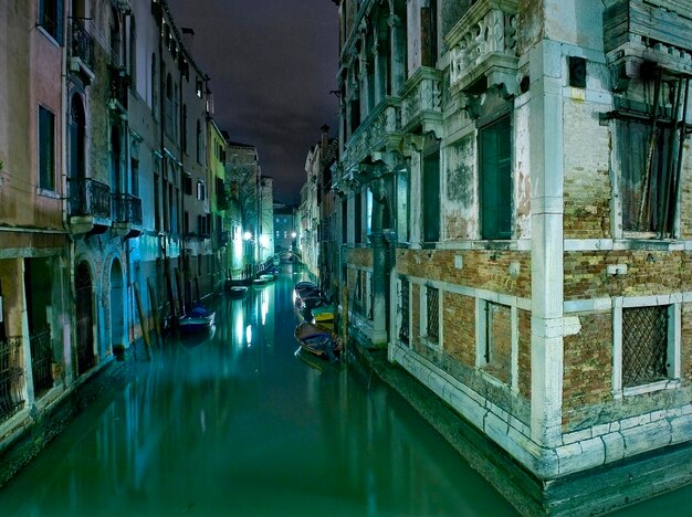 Foto boote, die nachts in einem kanal inmitten von gebäuden verankert sind