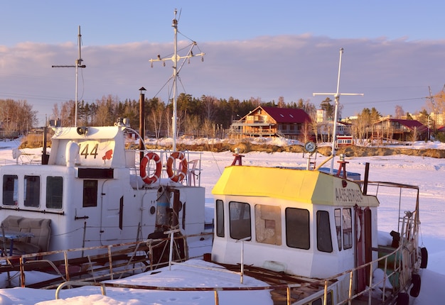 Boote und Yachten im Winter Flussboote verbringen den Winter am Ufer zwischen Schneeverwehungen