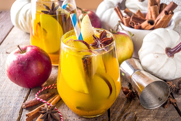 Boozy Pumpkin Party Punch, Thanksgiving-Sangria mit Kürbissaft, Apfel, Birne und Gewürzen, gemütlicher Holzhintergrund mit warmem Pullover und Zutatenkopierraum