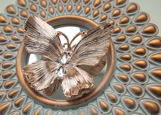 Borboleta dourada decorativa deitada em um espelho redondo