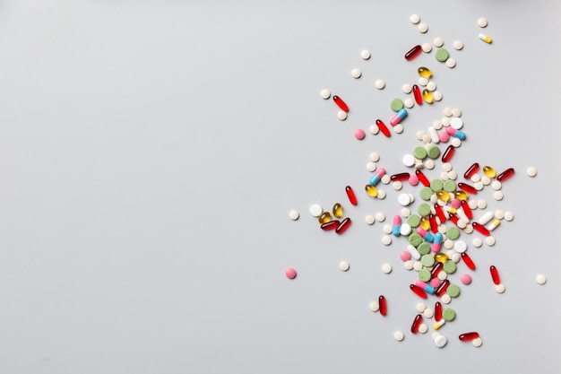 Borda superior de comprimidos e comprimidos variados sobre fundo colorido Muitos comprimidos diferentes e espaço para texto na vista superior de fundo colorido