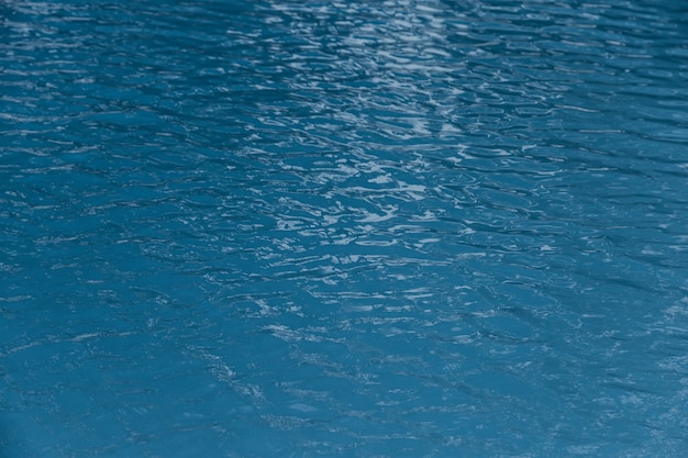 Borde azul de la piscina con el reflejo del fondo de la ondulación del agua