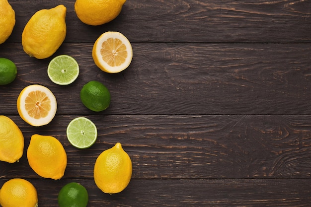 Borde de cítricos surtidos sobre fondo de madera rústica, copie el espacio. Vista superior de limones y limas, plano. Maqueta para receta de limonada exótica