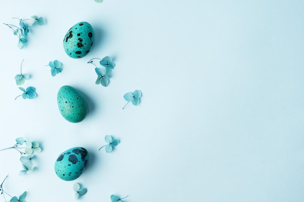 Borde hecho de huevos de codorniz de Pascua con flores de hortensia sobre un fondo azul Tarjeta de felicitación de Pascua