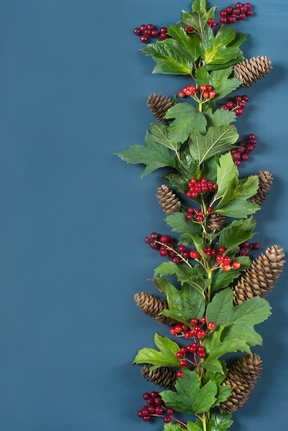 borde del marco decorativo, rama con frutos rojos, hojas verdes y conos de abeto