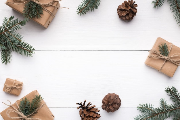 Borde de Navidad natural. Regalo de Navidad, piñas, ramas de abeto sobre fondo blanco de madera, vista superior, espacio de copia.