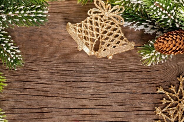Borde de Navidad de rama y campanas sobre fondo de madera