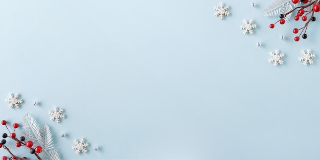 Borde navideño de copos de nieve y frutos rojos sobre fondo azul. Concepto de invierno. Endecha plana.