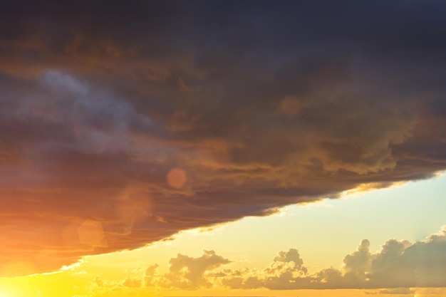 Borde oscuro y afilado de un frente de nubes tormentosas frente a una luz brillante del sol al atardecer