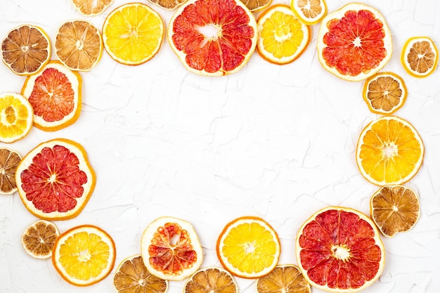 Borde de rodajas secas de varias frutas cítricas sobre fondo de marco blanco, naranja pomelo limón con copyspace