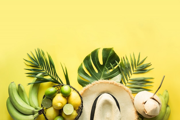 Borde de traje de playa tropical, accesorios femeninos, sombrero de paja para el sol, hojas de monstera en amarillo. Concepto de verano