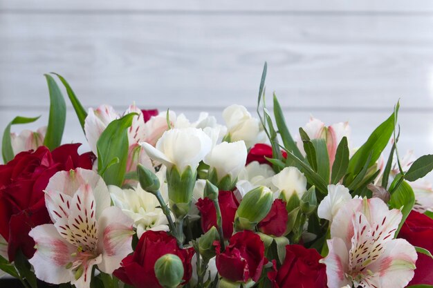 Borgoña brillante y flores de colores en un ramo sobre fondo de madera clara primer plano