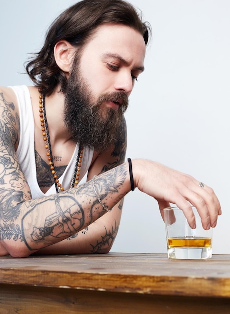 Borracho con barba y tatuaje hombre con vaso de whisky