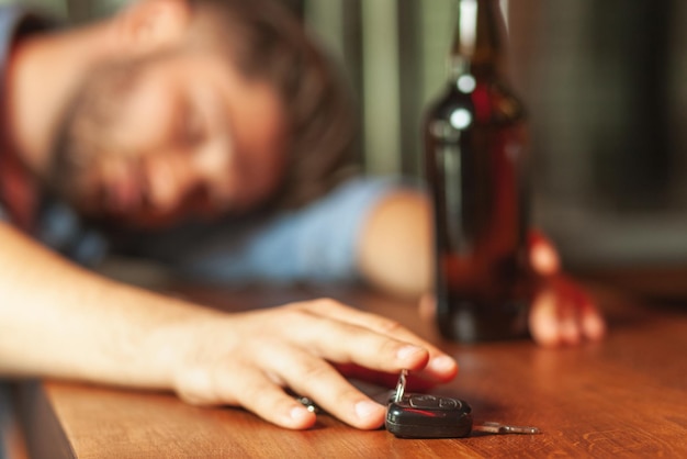 Borracho durmiendo en el mostrador del bar y sosteniendo las llaves del auto