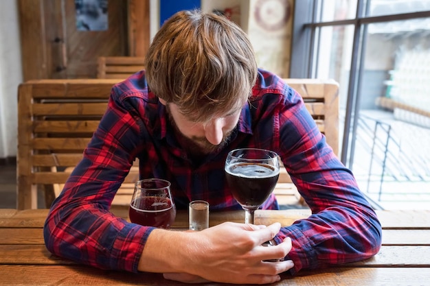 Un borracho solitario sentado en un bar con alcohol. Triste borracho deprimido