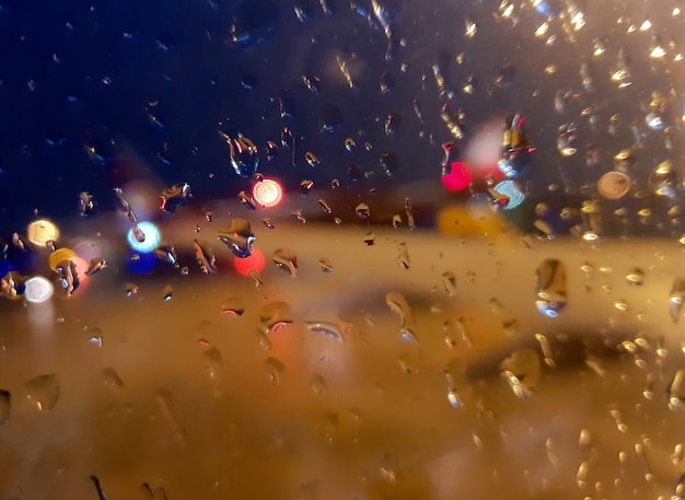 Borradas de vidraça molhada com pingos de chuva e bokeh glitter luz de fundo