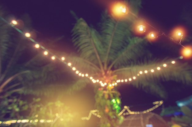 Foto borrão de luz com coqueiro, luzes da corda amarela com bokeh decoração no restau ao ar livre