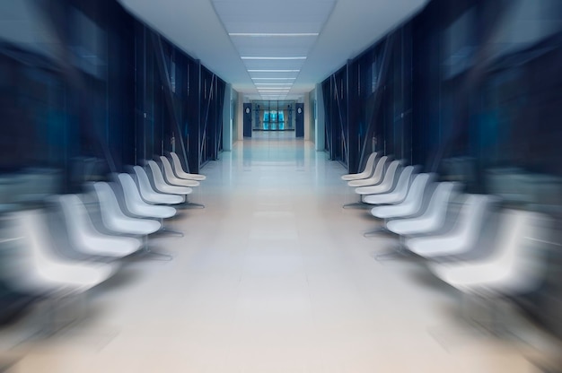 Foto borrão de movimento, lobby branco do hospital com uma porta e cadeiras brancas para pacientes esperando a visita do médico