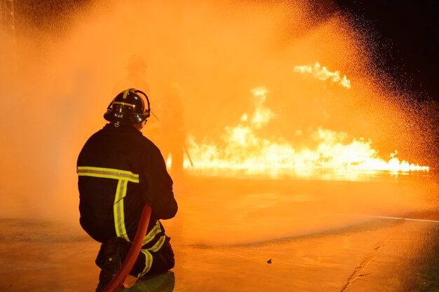 Foto borrões e silhuetas de bombeiros apagando incêndios e ajudando vítimas.