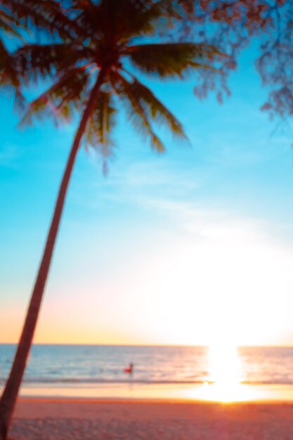Foto borroso de hermoso atardecer sobre el mar con palma en la playa tropical y cielo azul para viajar en vacaciones tiempo de relajación estilo foto vintagexa