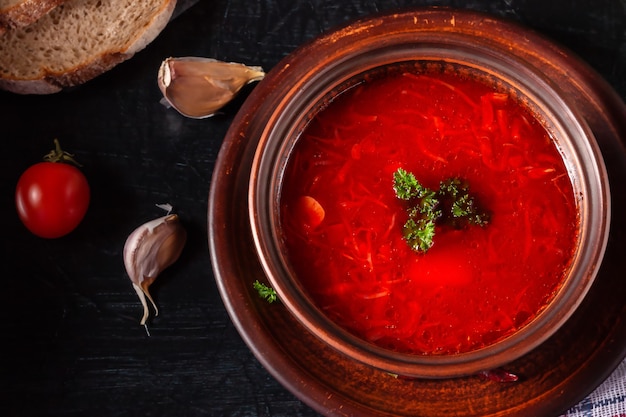 Borsch - Rote-Bete-Suppe in einer Tonschale auf einem Steinhintergrund, traditionelles Gericht der ukrainischen Küche.