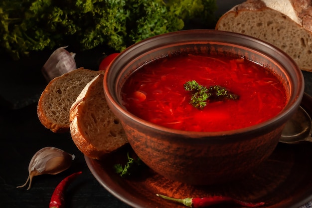 Borsch - sopa de beterraba em uma tigela de barro sobre um fundo de pedra, prato tradicional da culinária ucraniana.