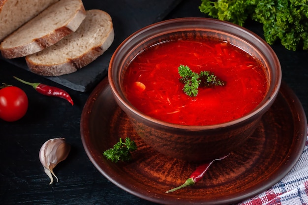 Borsch - sopa de beterraba em uma tigela de barro sobre um fundo de pedra, prato tradicional da culinária ucraniana.