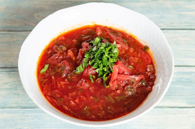 Borsch - sopa de remolacha en un recipiente blanco sobre fondo de madera