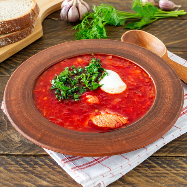 Borsch - sopa de remolacha tradicional ucraniana y rusa sobre fondo de madera oscura. Servido con pan de centeno, ajo y sal.