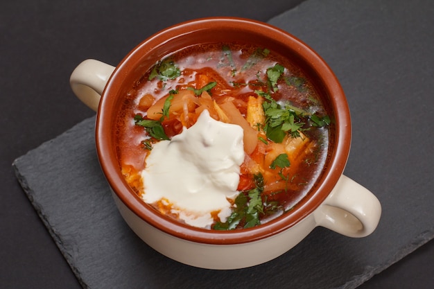 Borsch tradicional ucraniana com creme de leite em uma tigela de porcelana na placa de pedra. vista do topo.