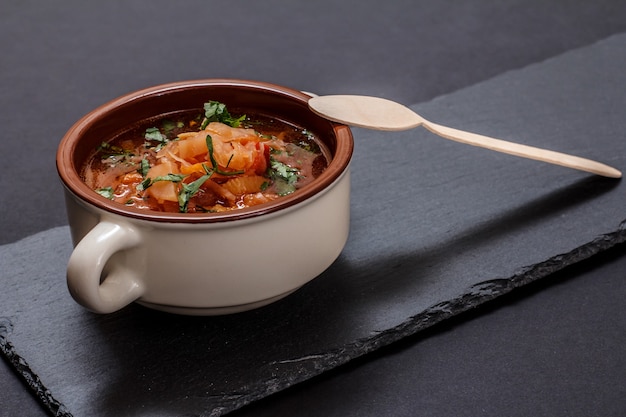 Borsch tradicional ucraniana em tigela de porcelana com colher de pau na placa de pedra. Vista do topo.