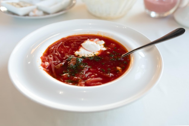 Borsch ucraniano sobre un mantel blanco como la nieve en un restaurante sazonado con crema agria