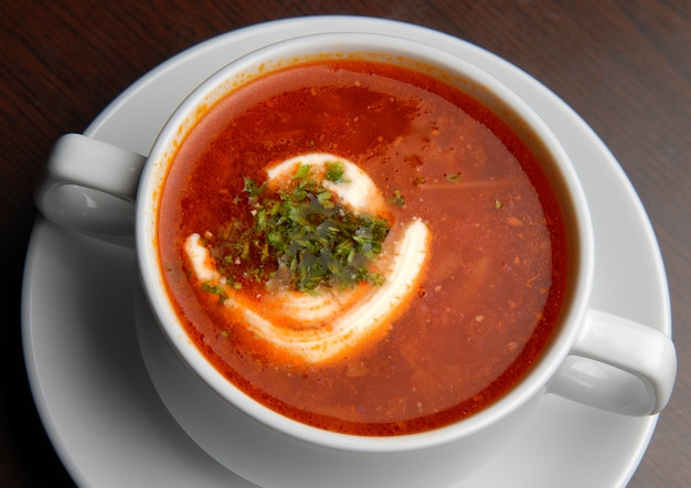 Borsch vermelho com creme de leite em um prato e pão