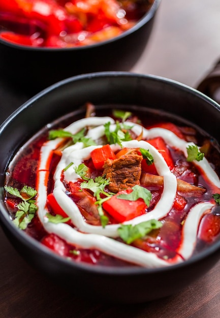 Borscht adornado con crema agria y perejil en un tazón negro.