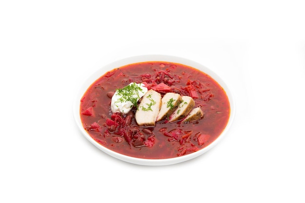 Foto borscht tradicional con remolacha, carne, frijoles, crema agria y hierbas aisladas sobre fondo blanco, cena caliente.