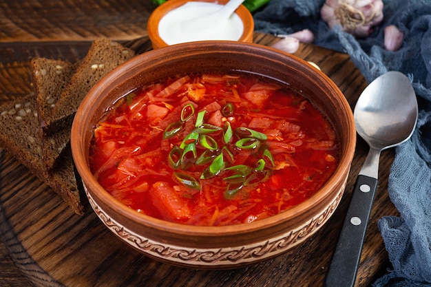 Borscht tradicional ucraniano con cebolla verde y crema agria Deliciosa sopa de remolacha en un tazón con pan de centeno